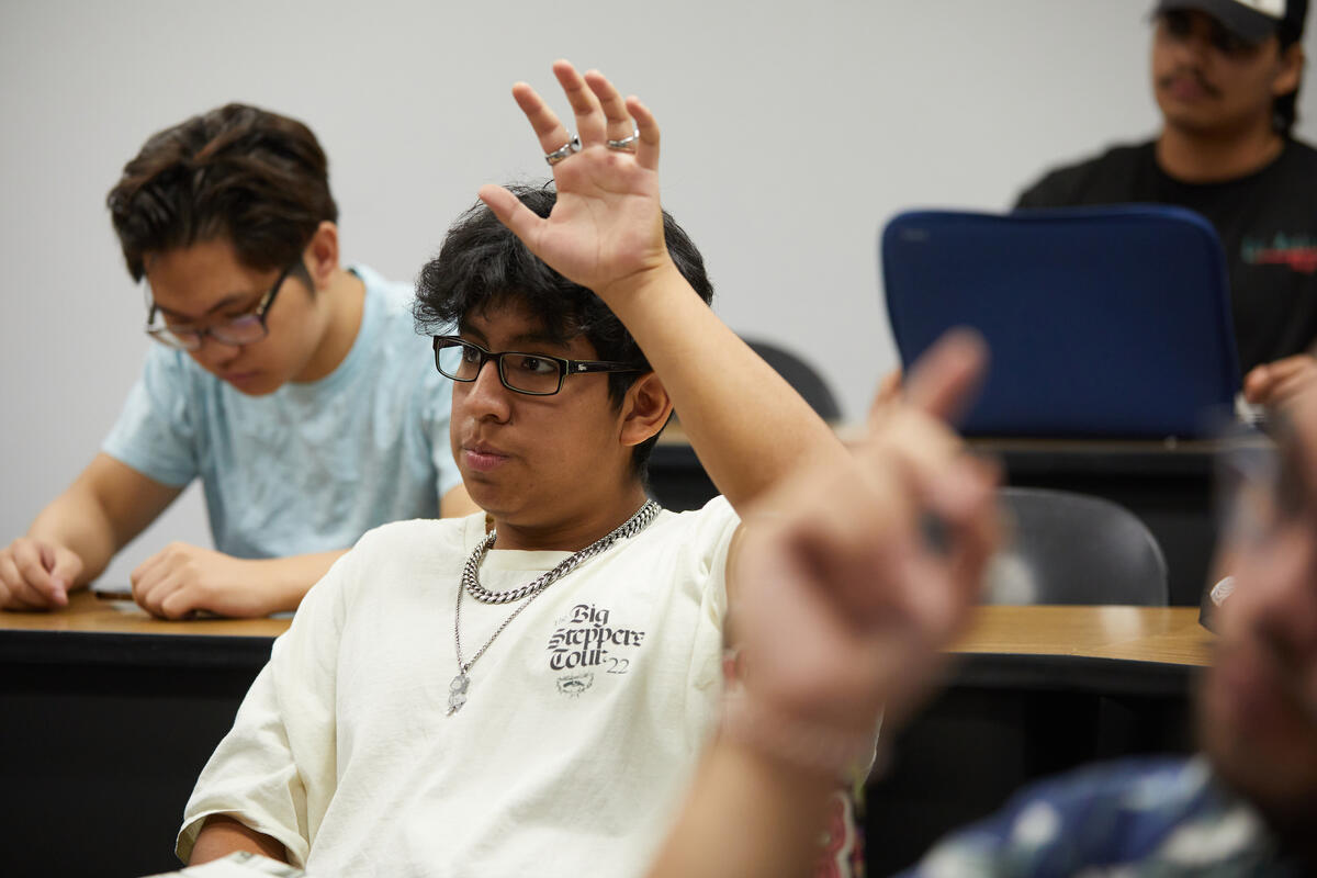 A person raising their hand in a classroom